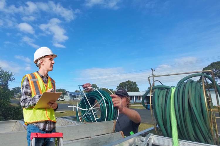 
Post-gutter rinsing, merimbula gutter cleaner loads up his hose system.